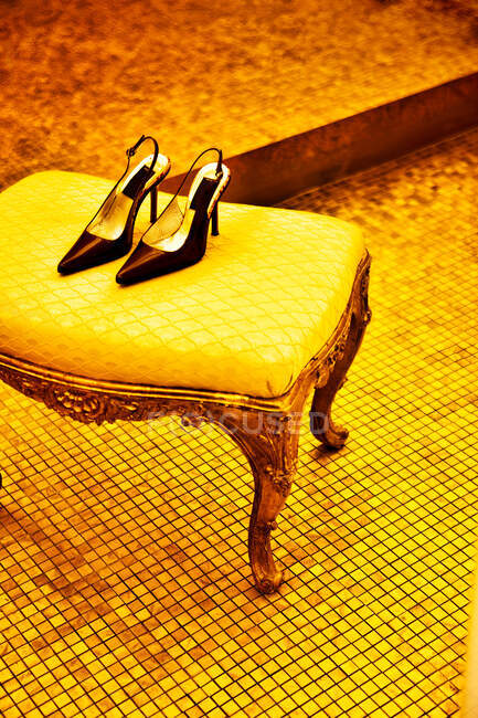 High heel shoes on parquet near chair — Stock Photo