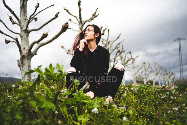 Портрет молодой женщины во сне, сидящей в зеленом поле в пасмурном облаке — стоковое фото