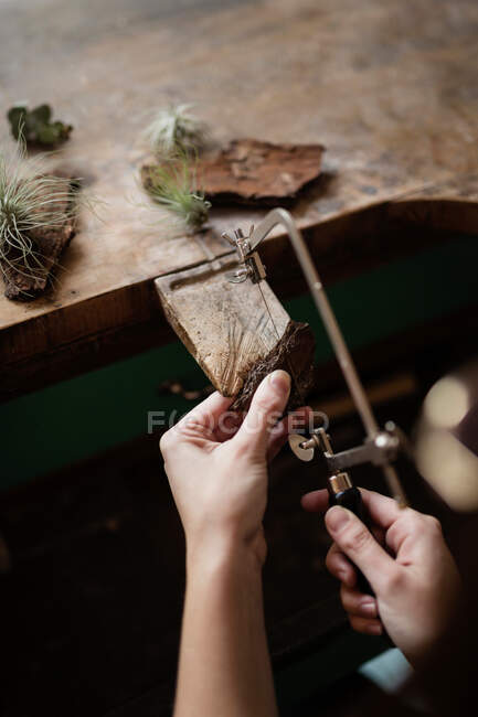Обрізати крупним планом руки людини різьблення прикраси шматка дерев'яної кори з інструментом на стіл — стокове фото