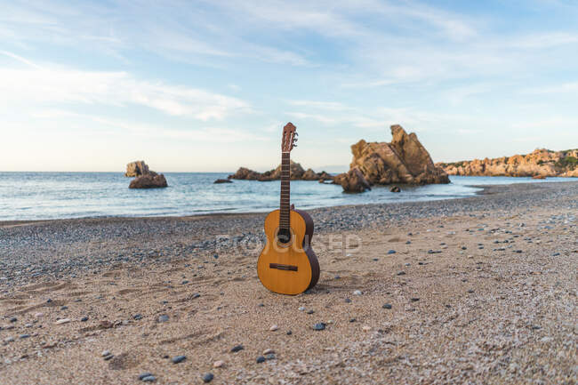 Guitarra acústica clássica colocada no oceano em uma praia. — Fotografia de Stock
