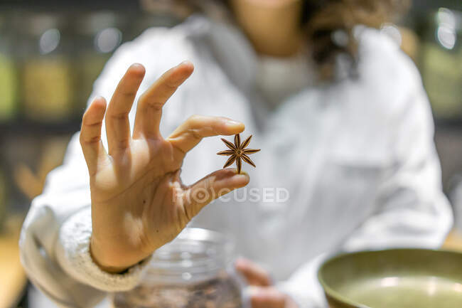 Femme méconnaissable tenant une étoile d'anis dans un magasin d'épices. — Photo de stock