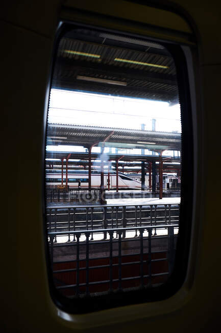 Roofed railway station with modern train arriving through window — Stock Photo