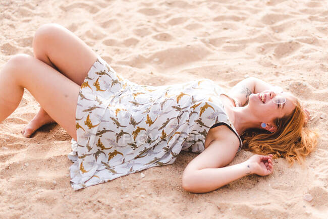 Side view of crop woman kicking sand while lying and relaxing on sandy coast — Stock Photo