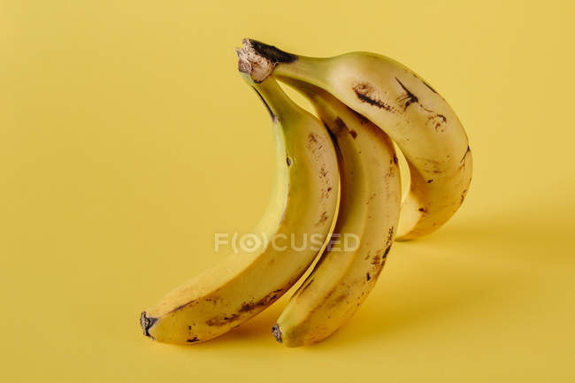 Bando de bananas maduras em fundo amarelo vívido — Fotografia de Stock