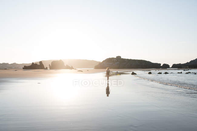 Silhouette de femme femme sur sable mouillé près de la mer par jour ensoleillé — Photo de stock