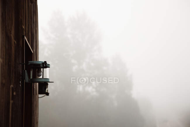 Piccola lampada appoggiata su parete di legno in nebbia pesante in Cantabria, Spagna — Foto stock