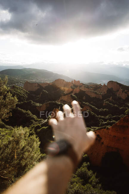 Schnittansicht eines verschwommenen Mannes, der seine Hand auf malerischen Skalen zwischen Wäldern in Kantabrien, Spanien, nach vorne zieht — Stockfoto