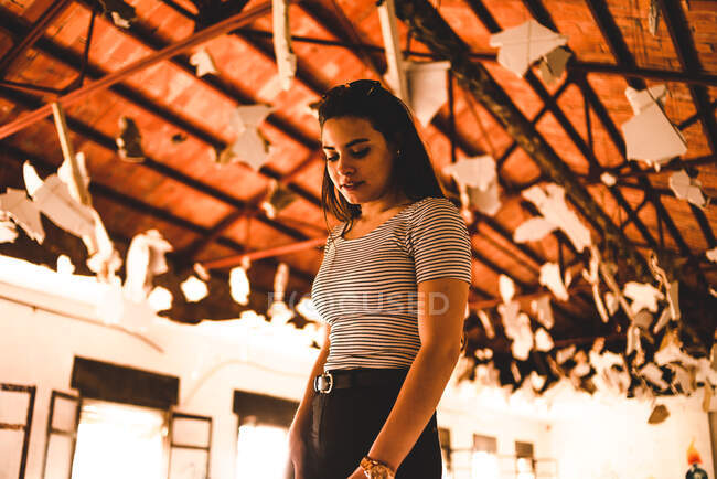 Charmante junge Frau steht unter dekoriertem Dach des hellen Pavillons und blickt nach unten — Stockfoto