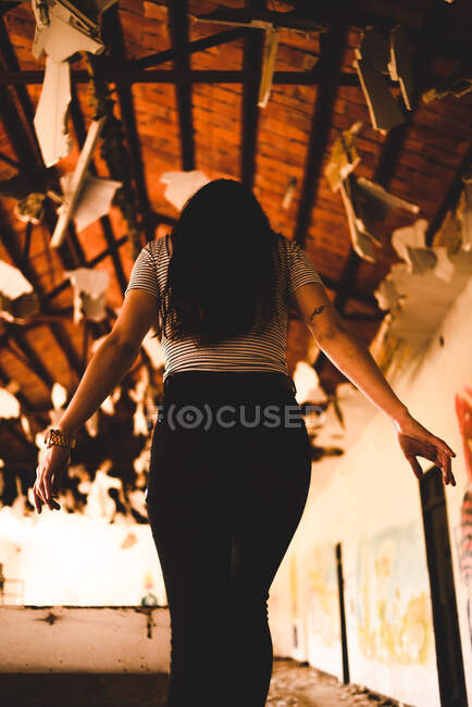 Encantadora joven de pie bajo techo decorado de pabellón de luz y mirando hacia abajo - foto de stock