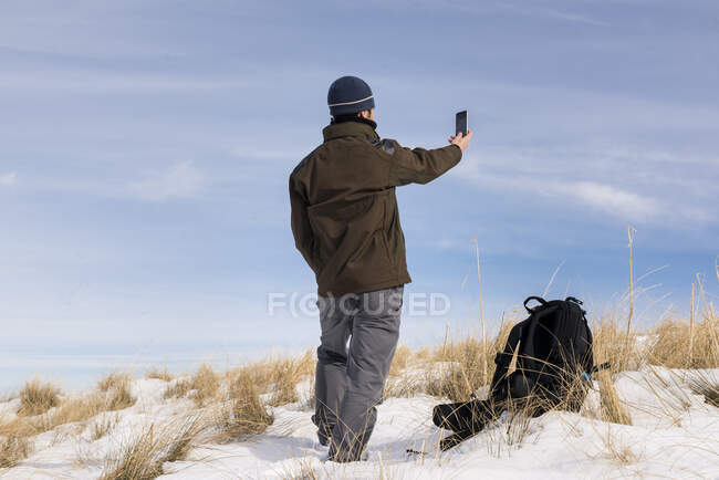 Wanderer mit Handy in verschneiten Bergen an einem sonnigen Wintertag. — Stockfoto