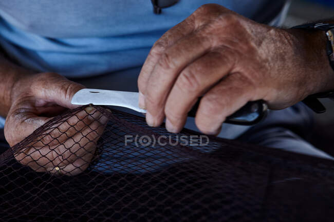 Урожай сверху вид человека, держащего в руках рыболовные сети и режущего ножом — стоковое фото
