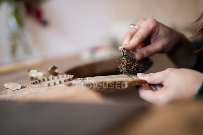 Crop close up hands of woman carving and brushing little detail with brush at desk — Stock Photo