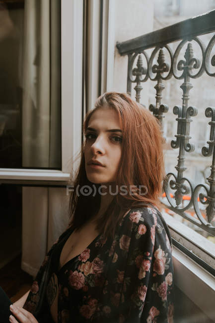 Portrait of Young woman standing at window — Stock Photo