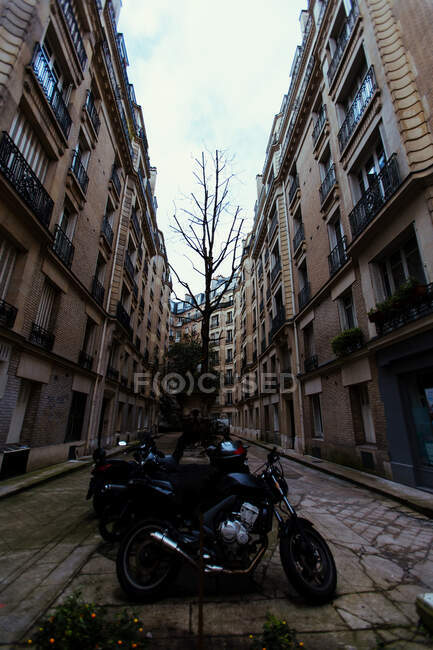 Different motorcycles parked on narrow street in Paris, France. — Stock Photo