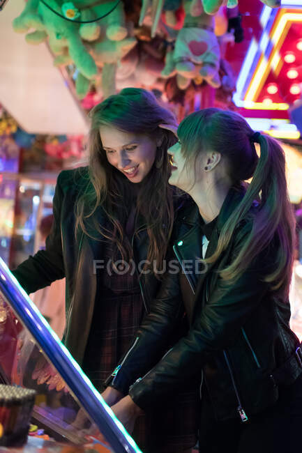 Cheerful young women having fun while playing amusement machine in park — Stock Photo