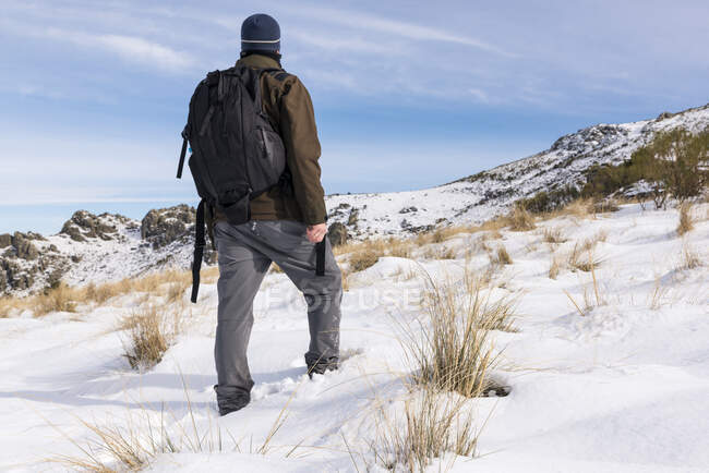 Giovane con uno zaino escursionismo godendo nelle montagne innevate in una giornata di sole invernale. — Foto stock