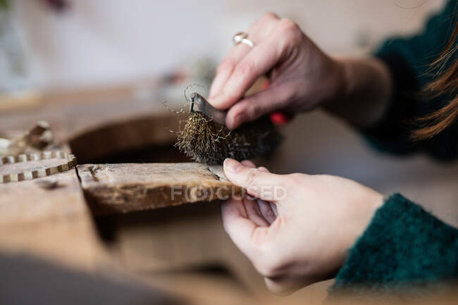 Crop close up hands of woman carving and brushing little detail with brush at desk — Stock Photo