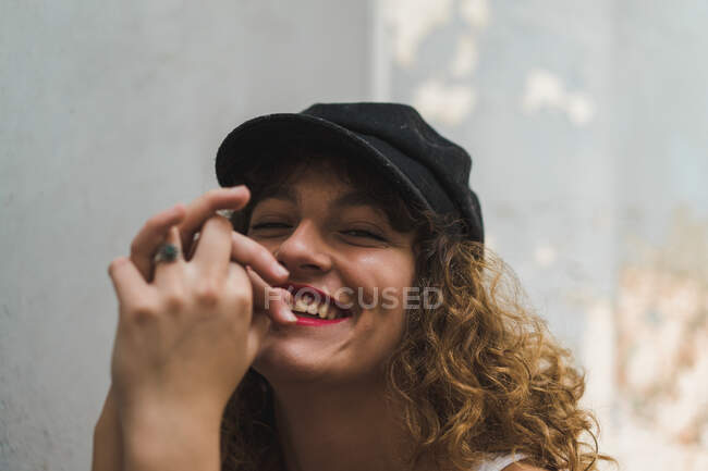 Primer plano de la joven mujer sin emociones con lápiz labial rojo y rizos voluminosos mirando a la cámara - foto de stock