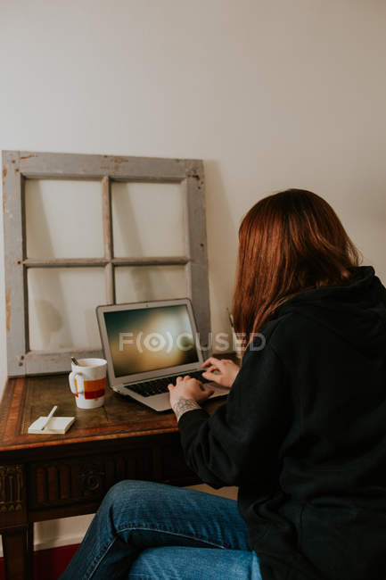 Jeune femme tapant sur ordinateur portable à la table vintage — Photo de stock
