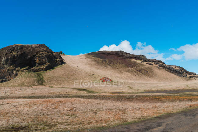 Paesaggio di piccola casa rossa a valle ai piedi delle montagne in Islanda — Foto stock