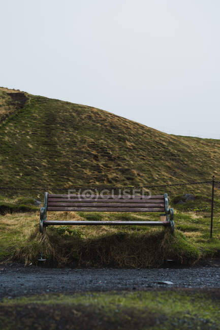 Gute Holzbank am Rande der Schotterstraße in schöner isländischer Landschaft an grauen Tagen — Stockfoto