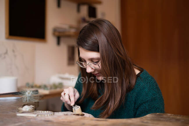 Ritaglio mani ravvicinate di donna intaglio dettaglio in legno con coltello alla scrivania — Foto stock