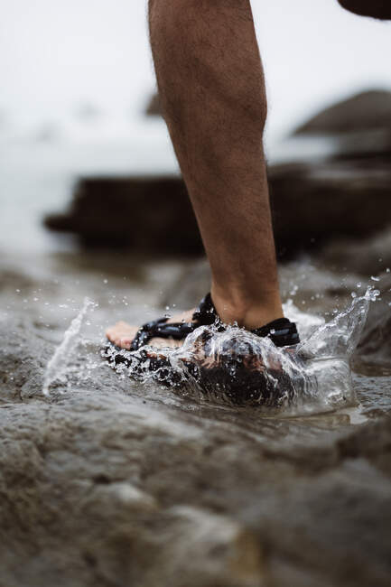 Primo piano del piede di persona in infradito spruzzi d'acqua in Cantabria, Spagna — Foto stock