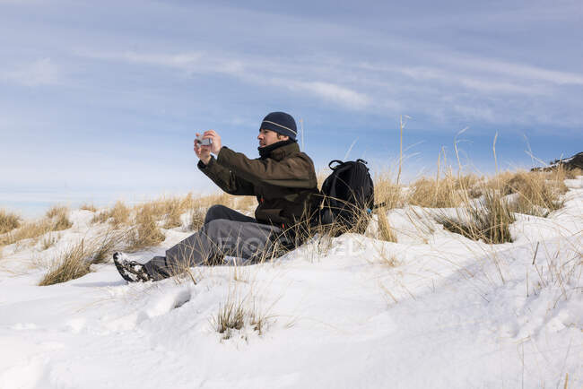 Escursionista con cellulare nelle montagne innevate in una giornata invernale soleggiata. — Foto stock