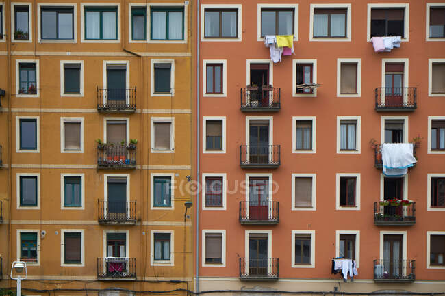 Желтый и красный фасад дома с окнами и одеждой, висящей на балконных перилах — стоковое фото