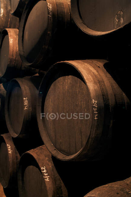 Wooden barrels with cherry liqueur placed in pile in dark repository — Stock Photo