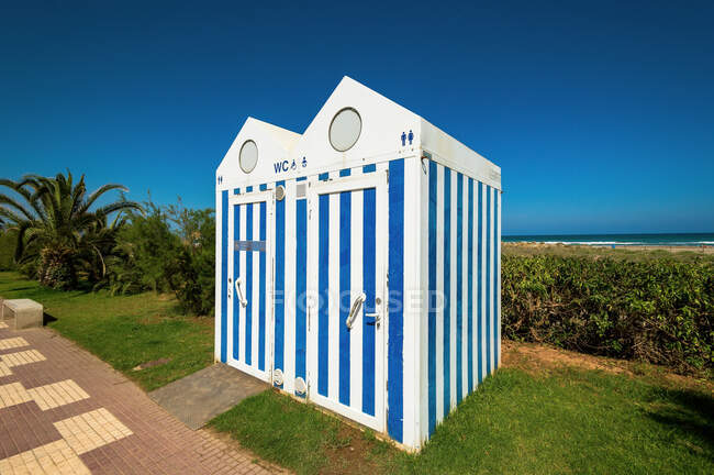 Dois banheiros públicos em pé na grama não muito longe da praia e do mar. — Fotografia de Stock