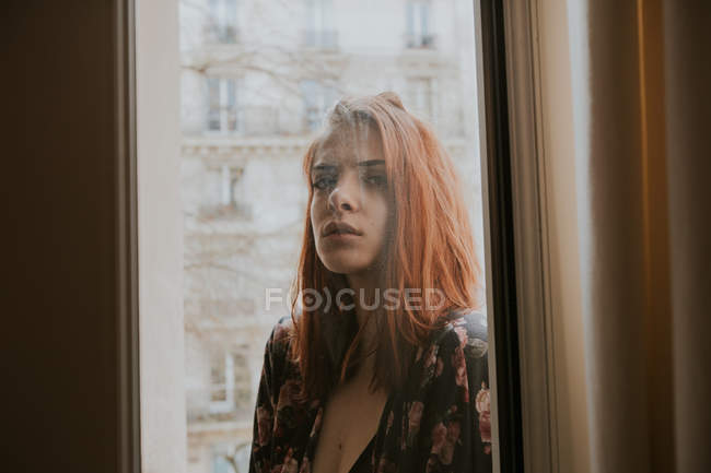 Woman standing at window — Stock Photo
