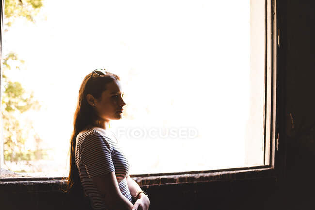 Silhouette of young woman standing near beautiful window in old building — Stock Photo