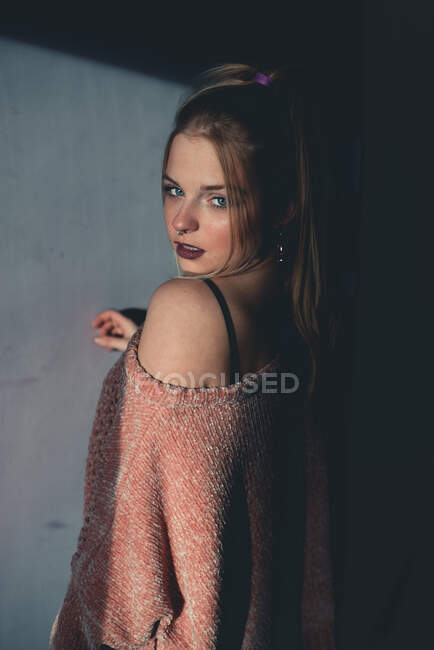 Attraktive junge hübsche Frau im Pullover posiert und blickt in die Kamera. — Stockfoto