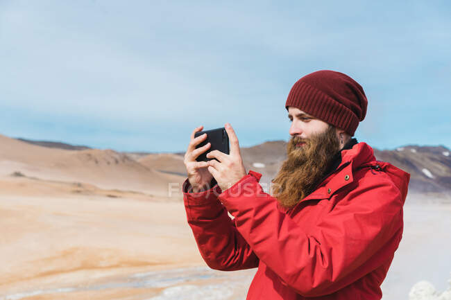 Man standing with smartphone at geyser — Stock Photo