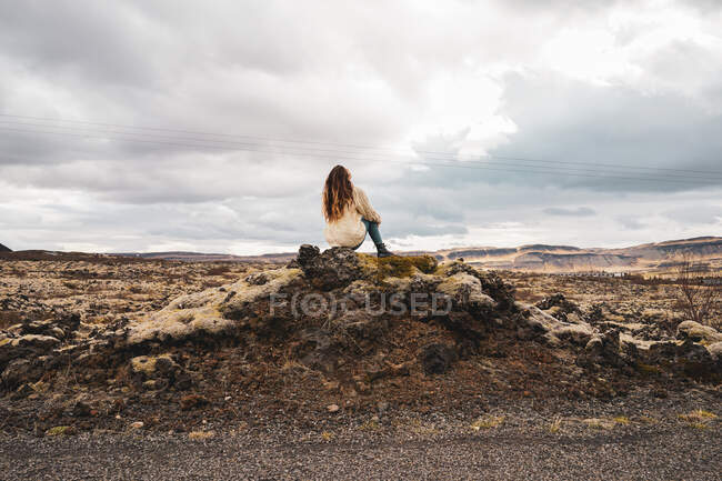 Woman sitting on picturesque stony background — Stock Photo