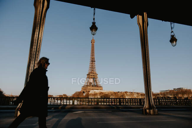 Vista lateral da mulher andando na rua no fundo da Torre Eiffel em Paris, França. — Fotografia de Stock