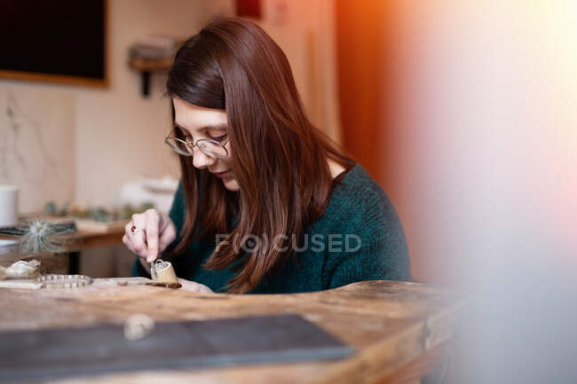 Crop close up hands of woman carving wooden detail with knife at desk — Stock Photo