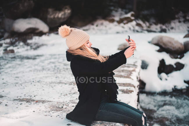 Frau macht Selfie am Fluss im Winter — Stockfoto