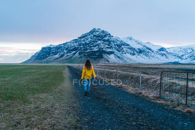 Donna sulla strada verso la montagna innevata — Foto stock