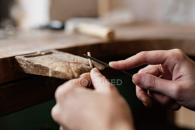 Урожай крупным планом руки человека, режущего палку ножом на столешнице — стоковое фото
