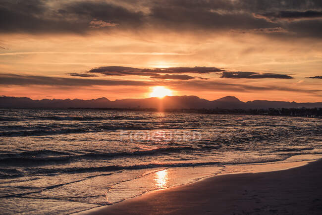 Increíble puesta de sol en la tranquila costa del océano - foto de stock