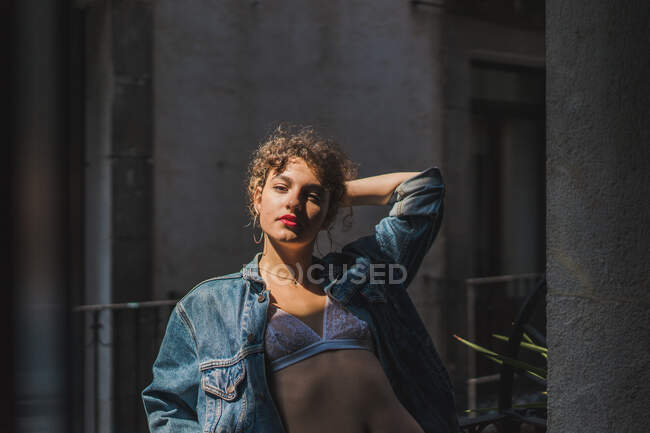 Young charming curly woman in lace underwear and with red lips looking at camera — Stock Photo