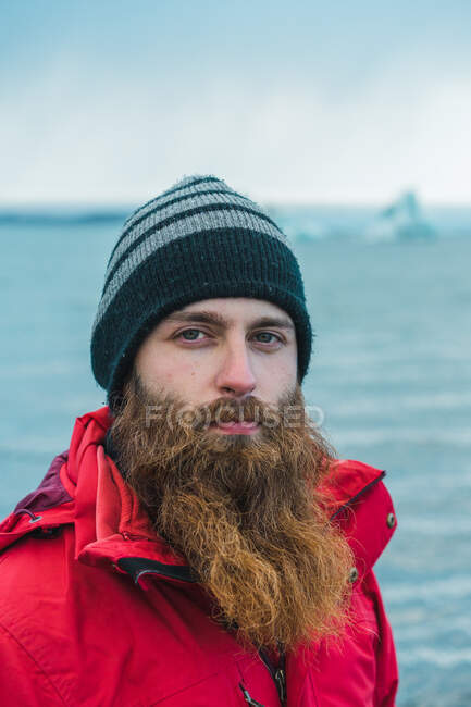 Hombre barbudo atractivo en ropa de abrigo por el agua - foto de stock