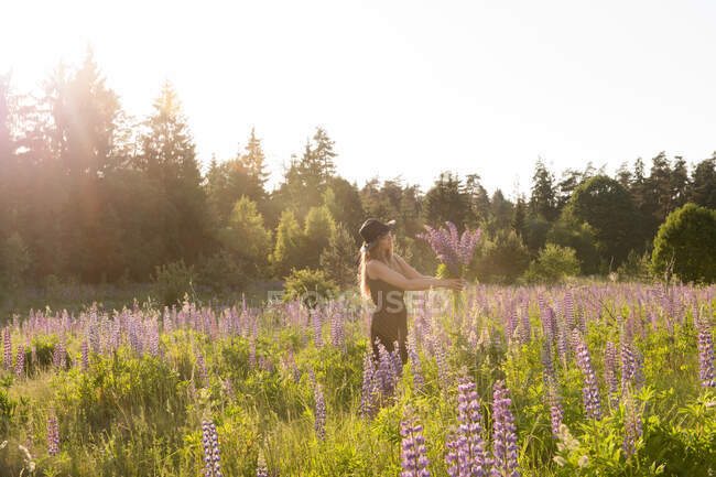 Frau mit Blumen bei strahlendem Sonnenschein — Stockfoto