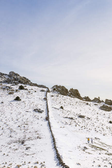 Les gens escaladent la montagne enneigée par une journée d'hiver ensoleillée — Photo de stock