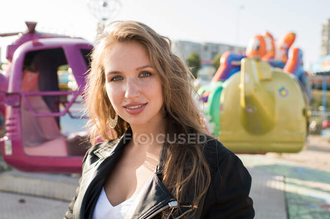 Jeune femme heureuse dans la rue contre magasin de parc d'attractions — Photo de stock