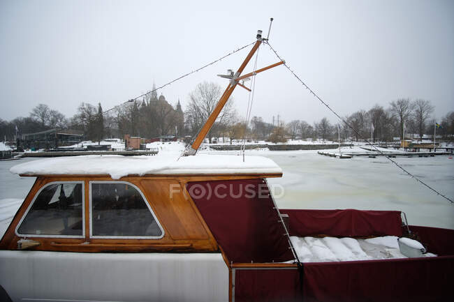 Nice wooden boat standing of frozen river in small Nordic town. - foto de stock