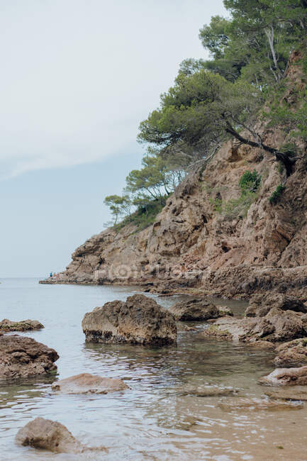 Erstaunlicher Blick auf Klippe mit Bäumen in der Nähe Muschelwasser des schönen Meeres in Tossa — Stockfoto