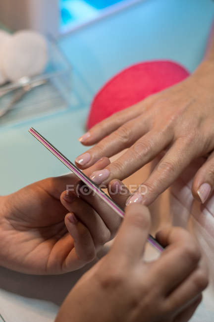 Female manicurist filing nails of client in beauty salon — Stock Photo